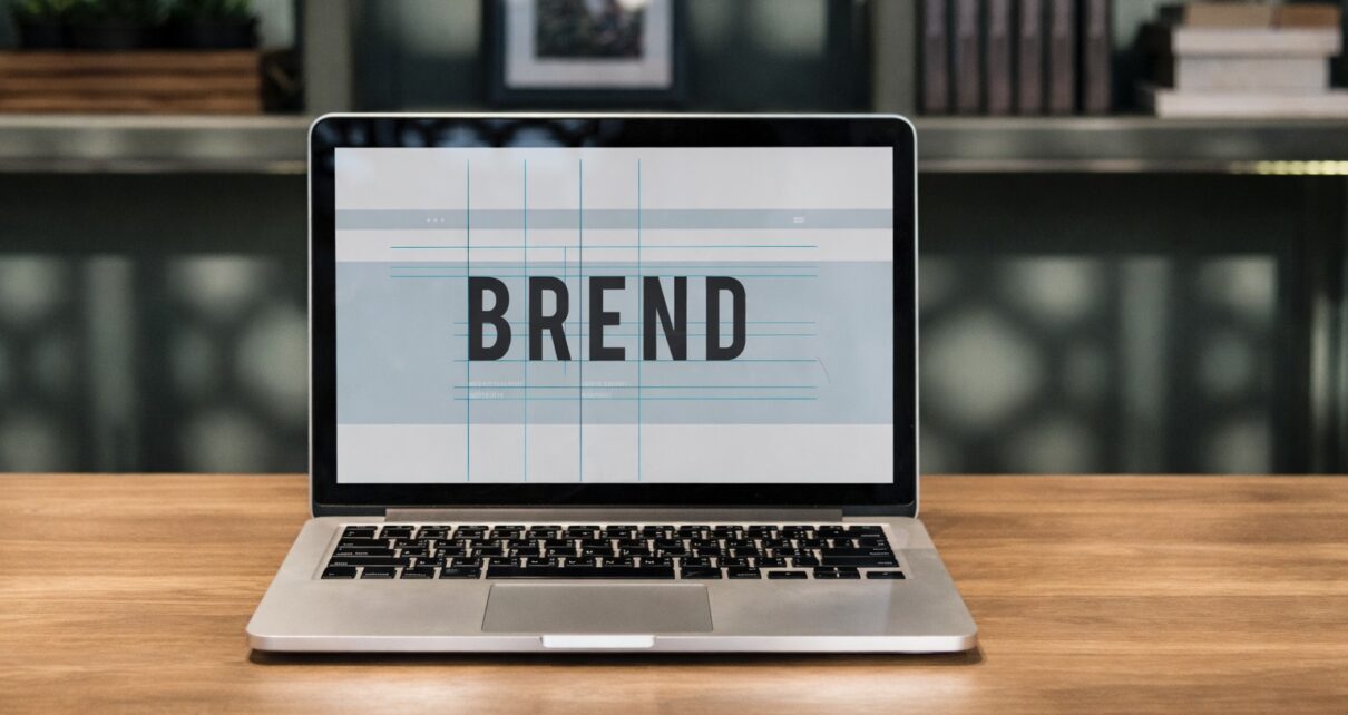 Laptop na stolu sa natpisom “BREND” na ekranu u modernom radnom prostoru