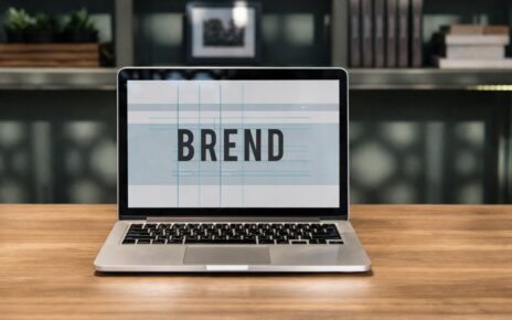 Laptop na stolu sa natpisom “BREND” na ekranu u modernom radnom prostoru