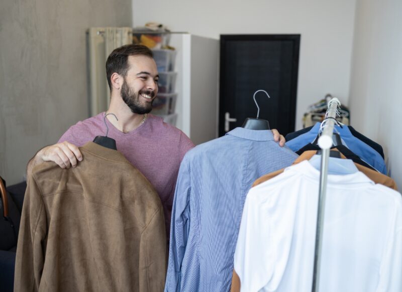 momak u svom garderoberu bira koju košulju i sako da obuče