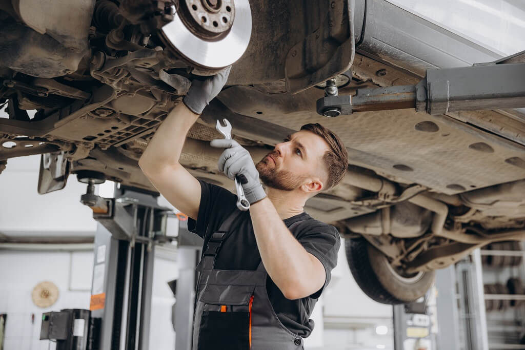 Mehaničar ispod automobila koji je na dizalici