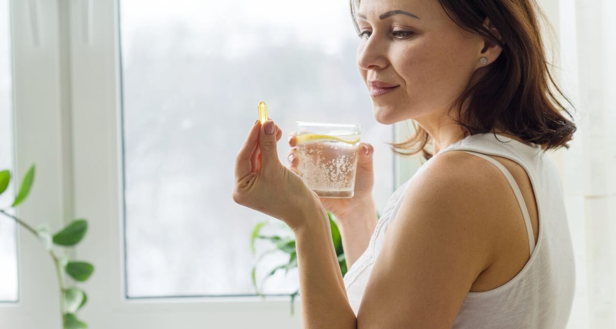 Žena drži kapsulu Ecomera u jednoj ruci u drugoj drži čašu vode