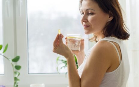 Žena drži kapsulu Ecomera u jednoj ruci u drugoj drži čašu vode