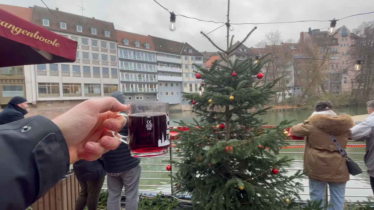 Čaša kuvanog vina ispred ukrašene jelke pored reke u Nirnbergu.